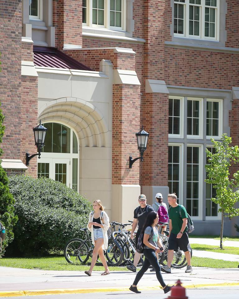 students walking past education building