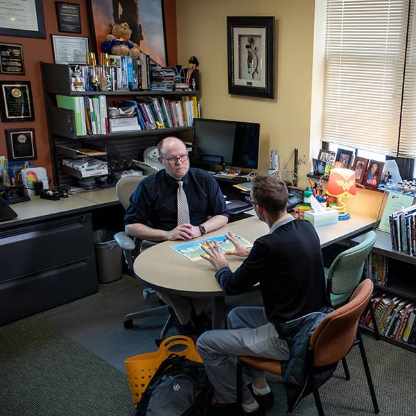 Graduate student talking to profession in office