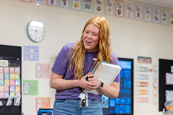 female teacher stands in front of elementary level classroom